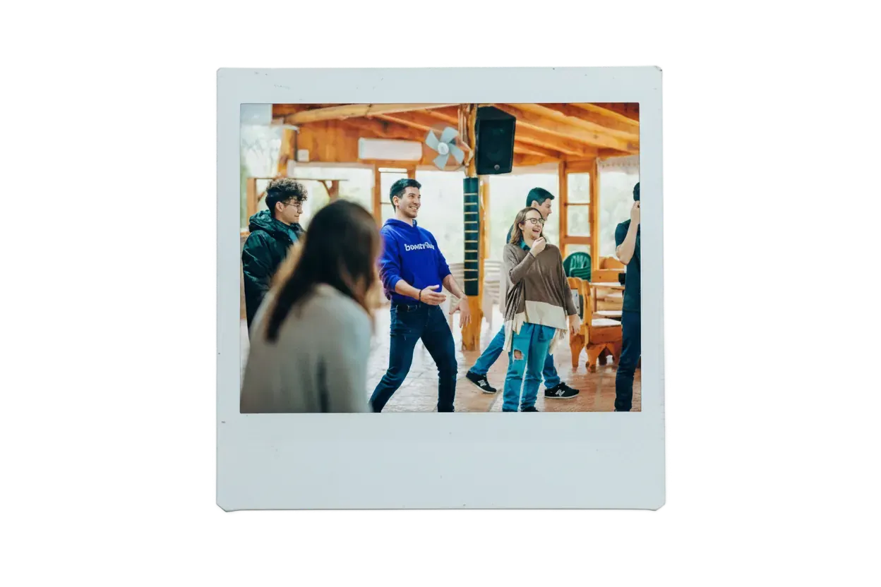 Grupo de personas riendo y moviéndose en una dinámica dentro de un salón de madera